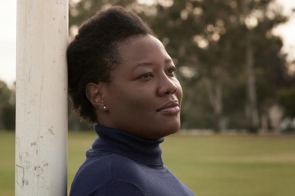 Ann Odong leaning against a post looking off camera