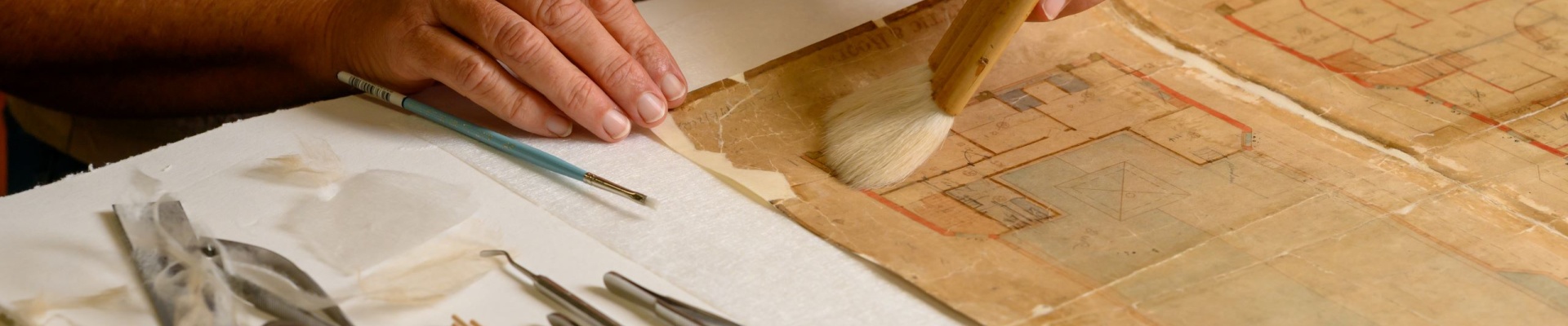 A person brushing a weathered manuscript