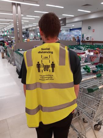 Staff member in Woolworths at The Mezz Shopping Centre Mount Hawthorn wearing jacket advertising social distancing