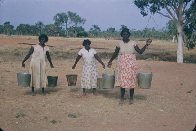 Three women carrying buckets of water