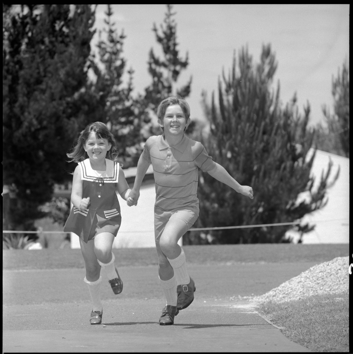 Boy and girl running while holding hands 1970