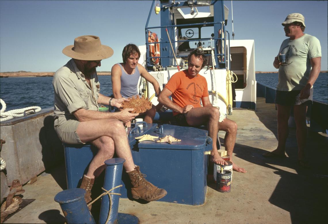 Harry Butler and others examining a starfish aboard a boat on the water near Barrow Island 1979