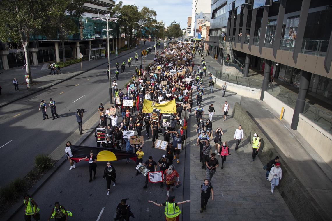 Protesters march along Wellington Street in front of the Perth Rail Station hemmed in by a cordon of police during the 3rd BLM rally on 4th July 2020