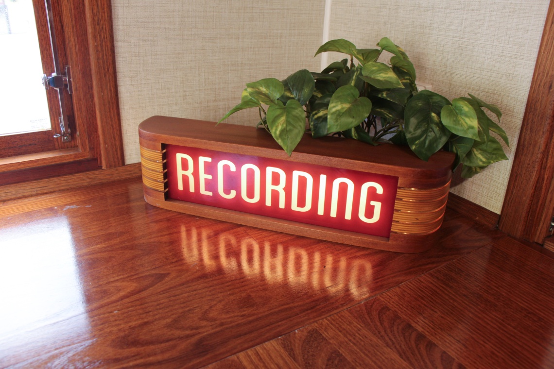 Neon red recording sign inside the Chin Wagon Mobile Story Studio