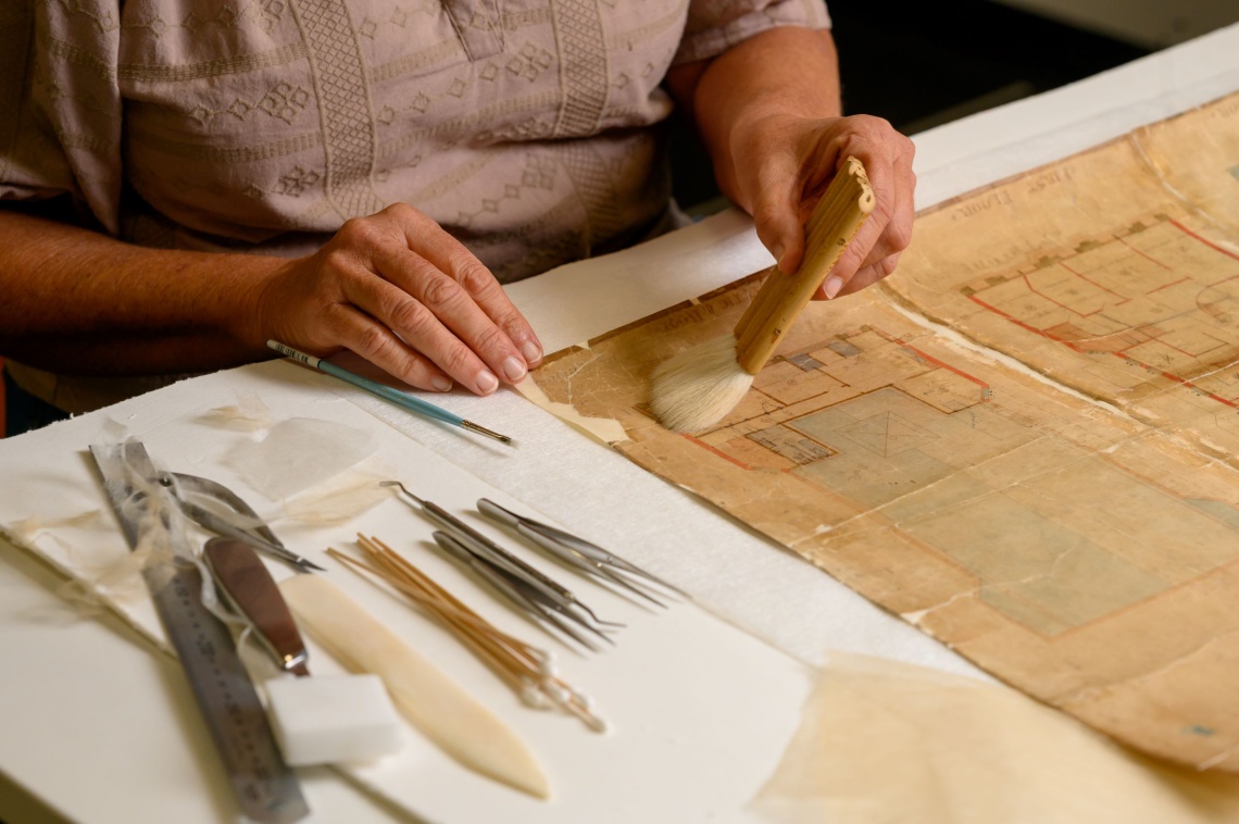 A person brushing a weathered manuscript