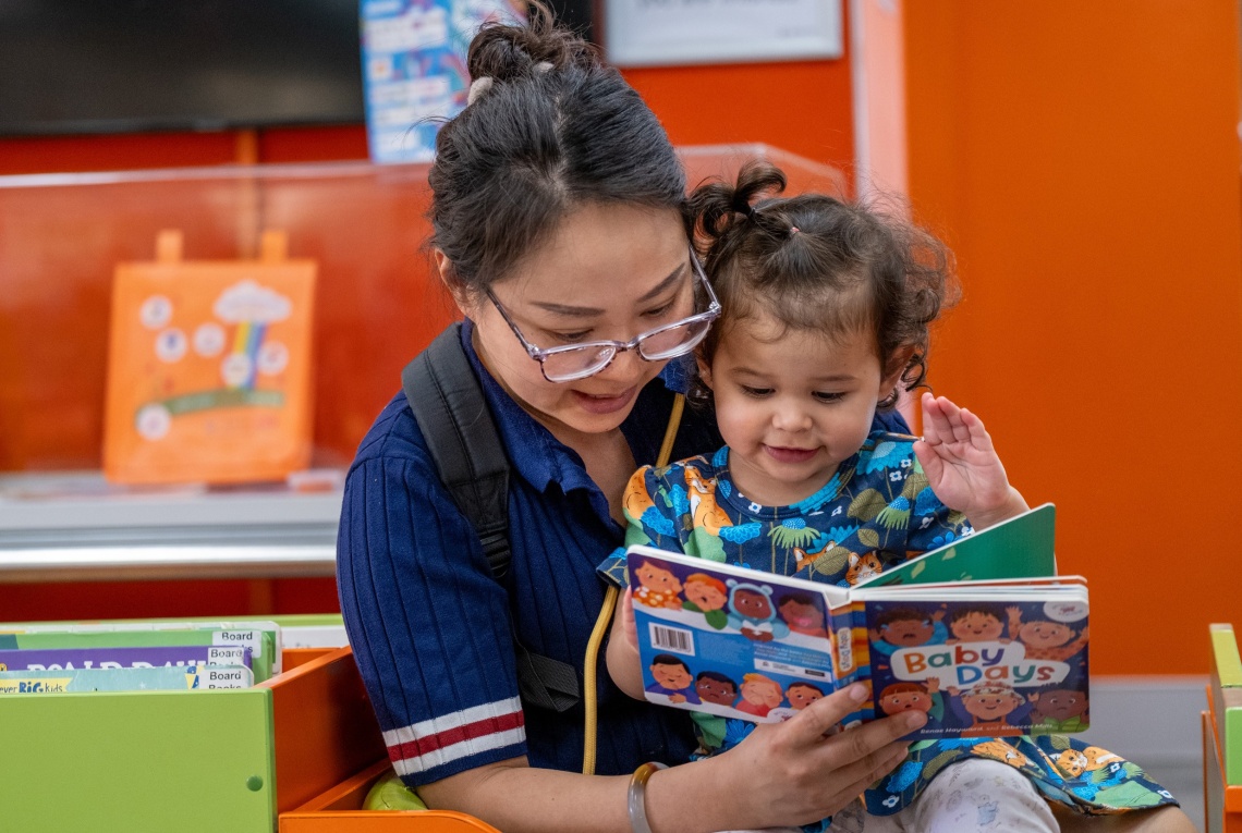 woman reads Baby Days book to child