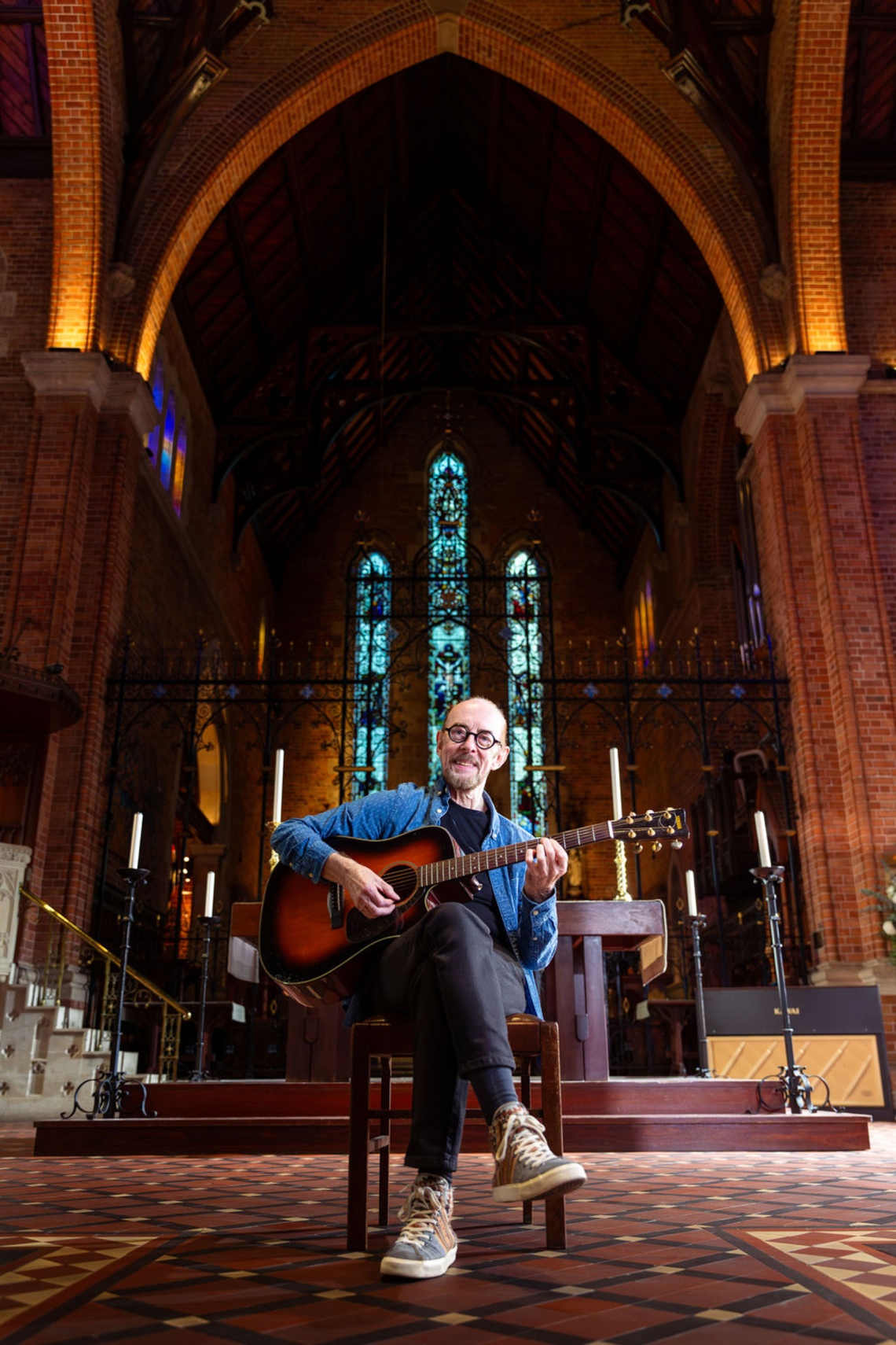 man with guitar sitting in a church