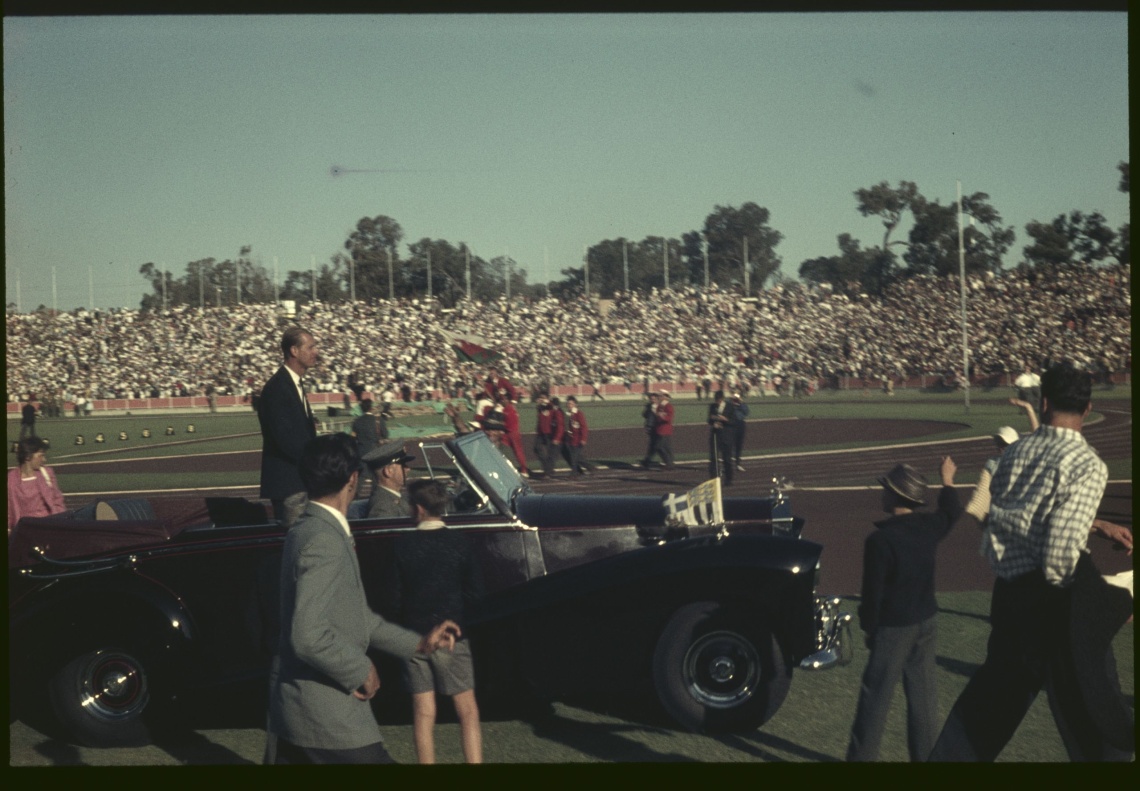 The Duke of Edinburgh standing in open car arrives at the opening ceremony 22 November 1962