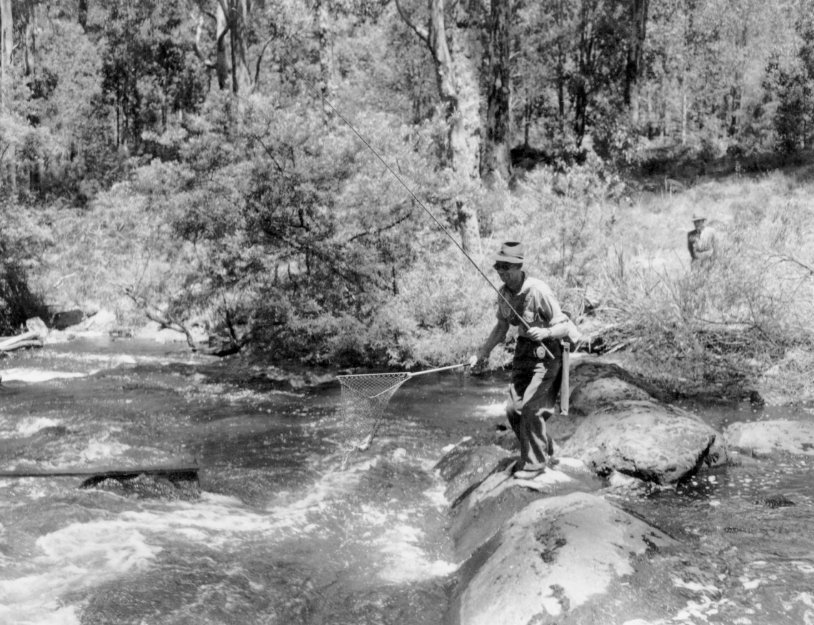 A man dynamically fishes off the rocks in the middle of a river