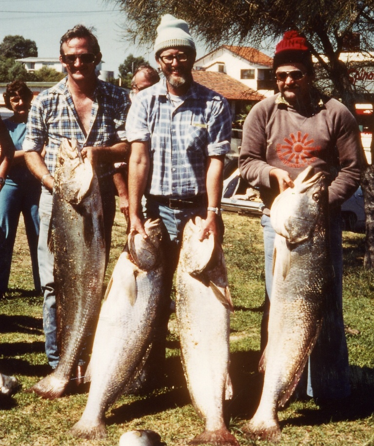 Three men hold up fish that are long enough to measure up to their hips