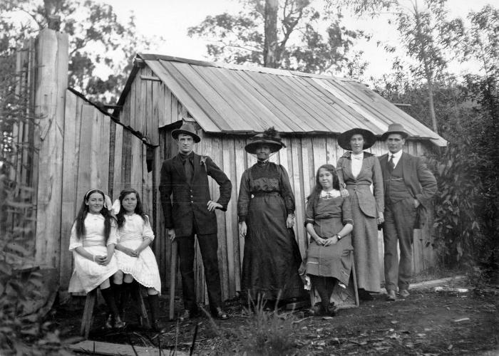 Settlers in front of a bush hut made from sawmill offcuts 1920s
