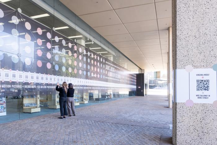 People scanning QR codes on the Alexander Library building