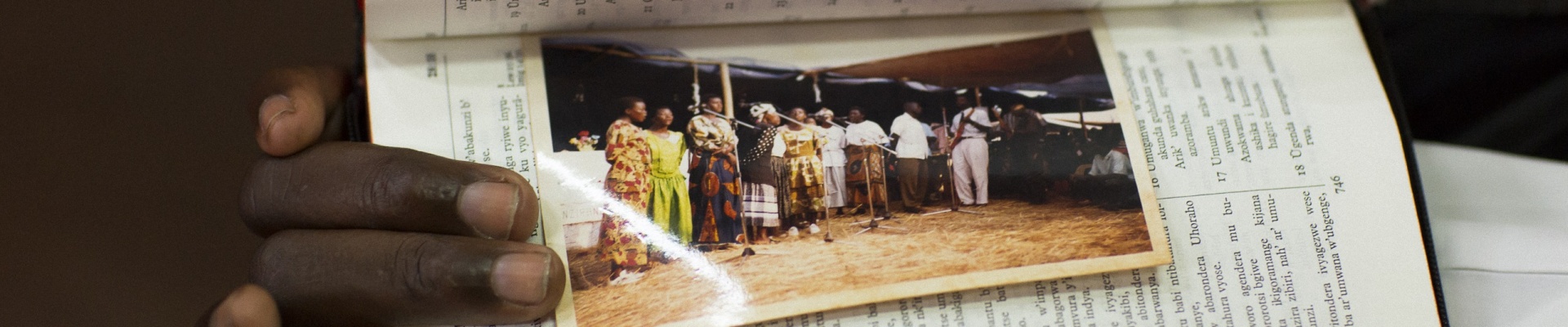 Holding a picture of choir members in the refugee camp of Tanzania where members spent up to 12 years before relocating to Australia 