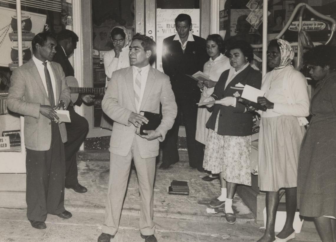 Jack Braeside Cedric Jacobs Valma Dimer Allan Bonney unknown unknown Gladys Vincent Lorna Davey Kathleen Green preaching in front of a shop